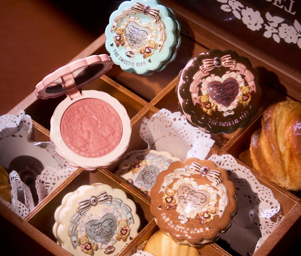 ```html
<img src="image.jpg" alt="Decorative makeup compacts with embossed designs in a wooden box, surrounded by pastries and doilies." />
```