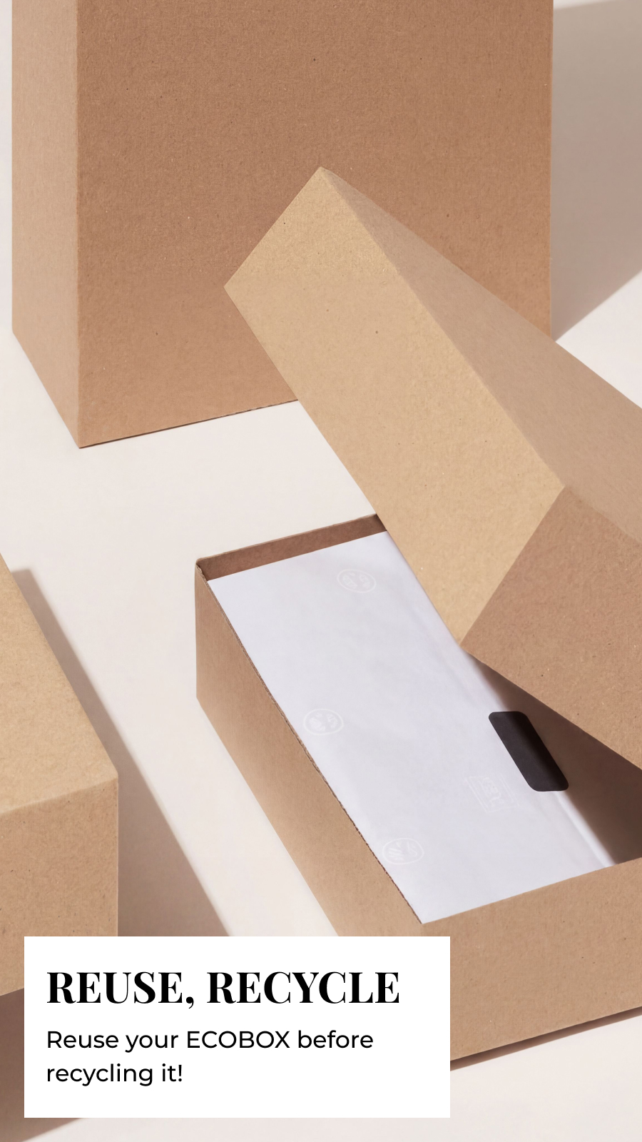 Kraft cardboard ECOBOX open with white tissue paper inside, surrounded by boxes, with "Reuse, Recycle" text below