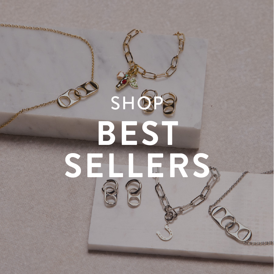 Jewelry display featuring gold and silver necklaces, bracelets, and earrings with geometric designs on a beige background. Text reads "Shop Best Sellers."