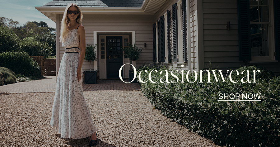 ```html
<img src="image.jpg" alt="Person in a long white dress standing outside a house with greenery, text 'Occasionwear, Shop Now' overlaid." />
```