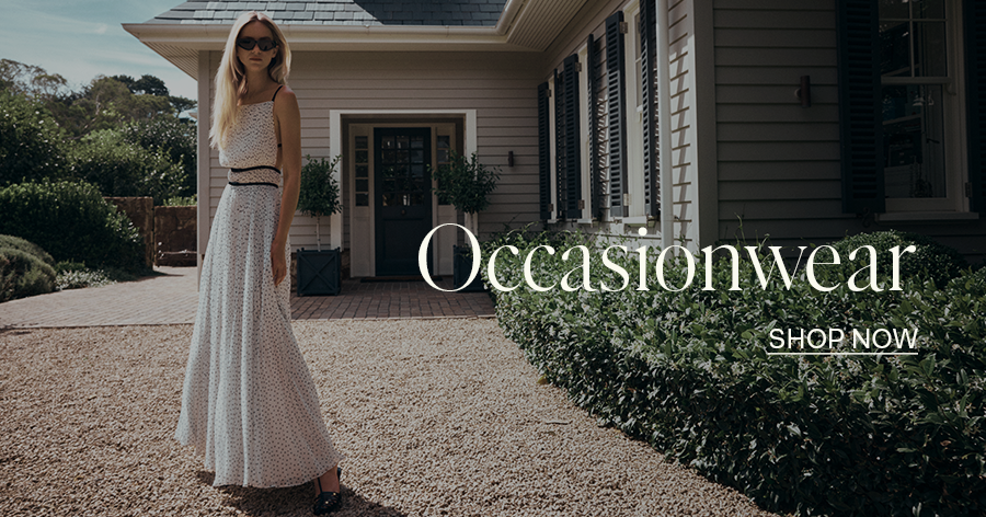 ```html
<img src="image.jpg" alt="Woman in elegant occasionwear dress standing on gravel path in front of a house, with text 'Occasionwear' and 'Shop Now' overlaid." />
```