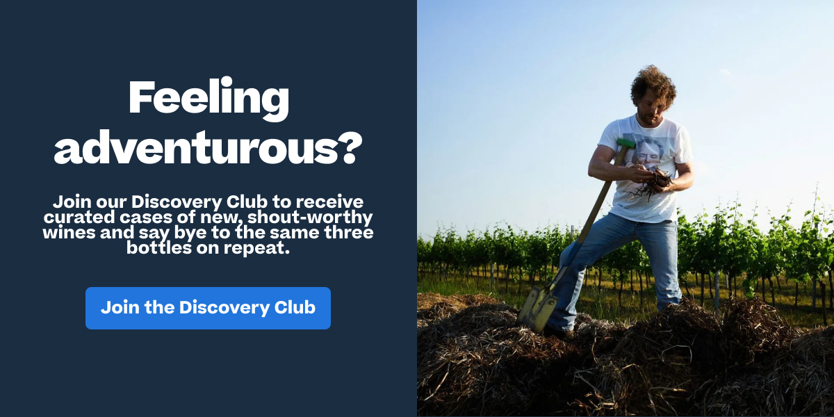 Man working with a shovel in a vineyard, next to a "Join the Discovery Club" wine subscription advertisement