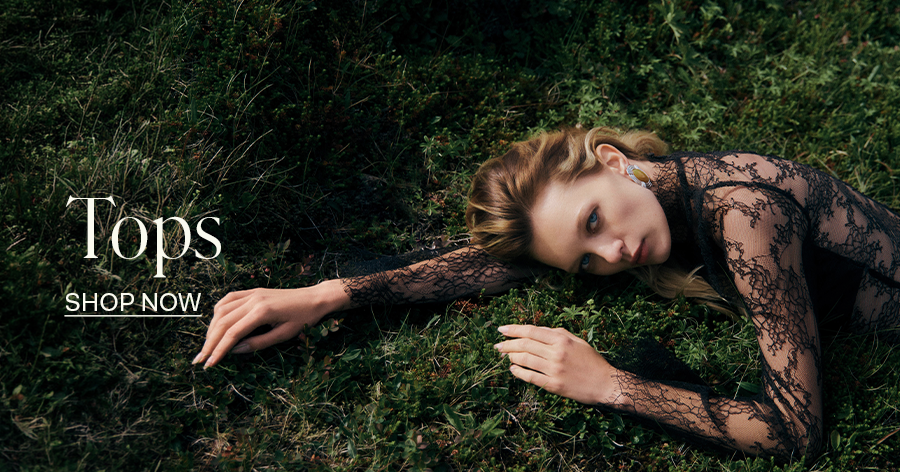 Woman in black lace long-sleeve top lying on grass, fashion "Tops - Shop Now" banner ad
