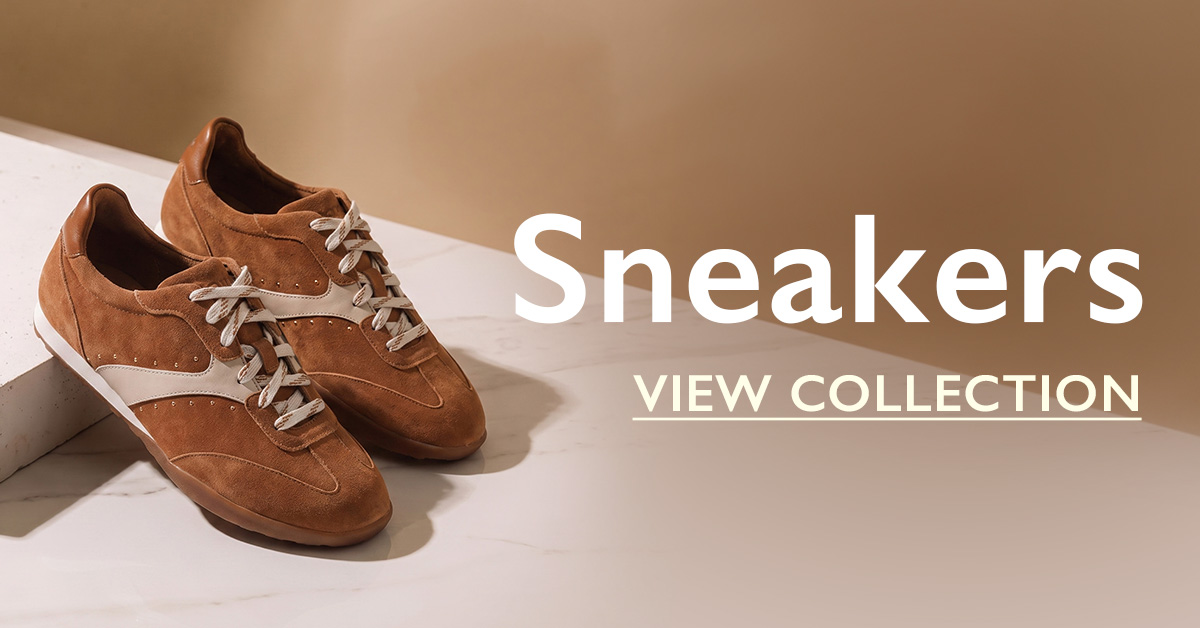 A pair of tan suede sneakers with cream laces on a marble surface, with text "Sneakers - View Collection"