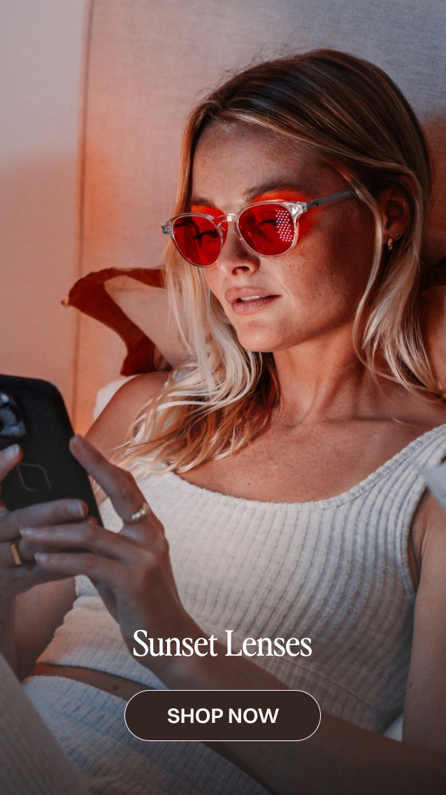 Woman wearing red-tinted sunset lenses sunglasses while using a smartphone, with a "Shop Now" button below.