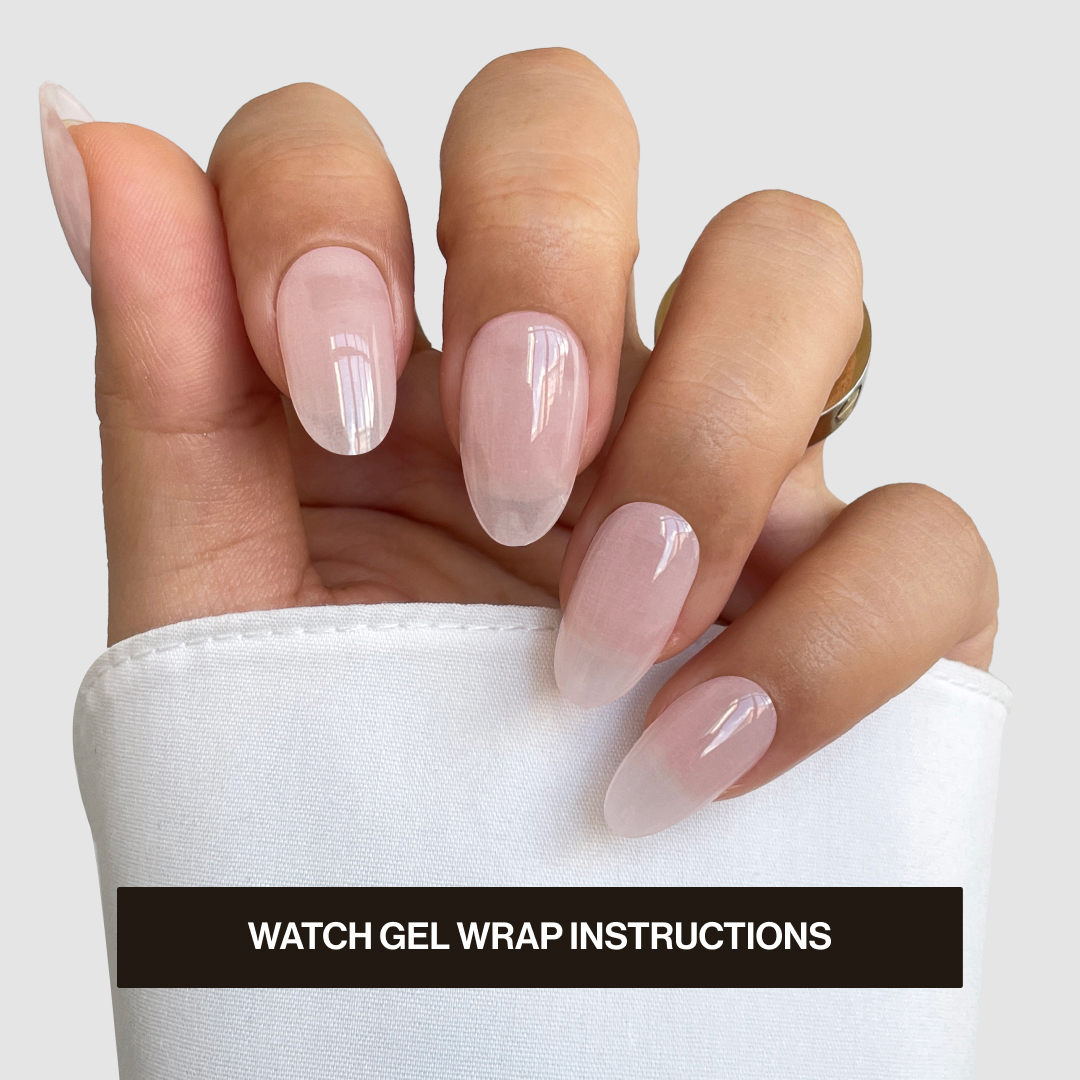 A hand with neatly manicured nails featuring a light pink gel wrap, wearing a white cuff and a gold ring. Text reads "WATCH GEL WRAP INSTRUCTIONS."