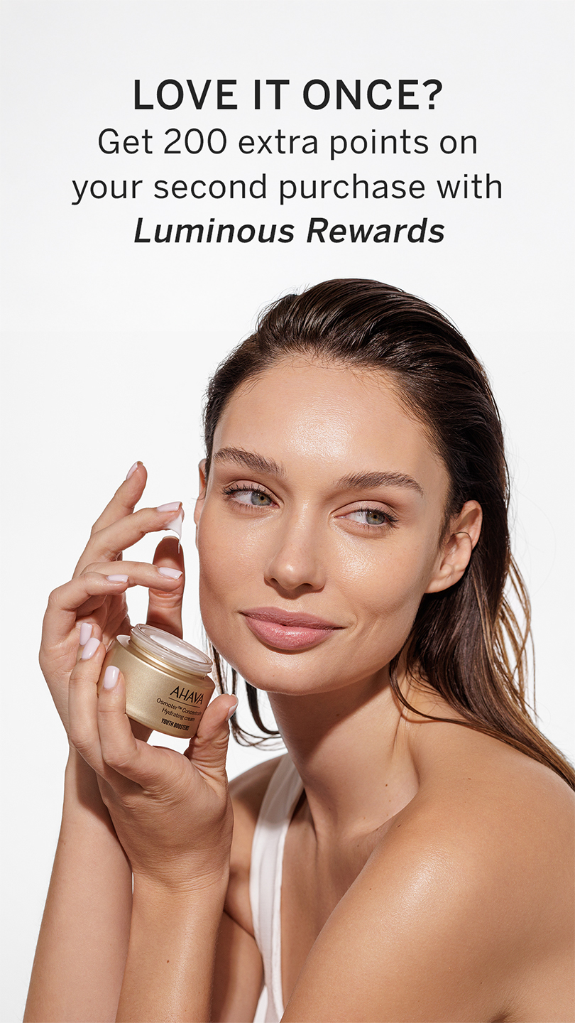 A woman applies cream from a golden jar labeled "AHA," promoting a rewards program with 200 extra points for a second purchase.