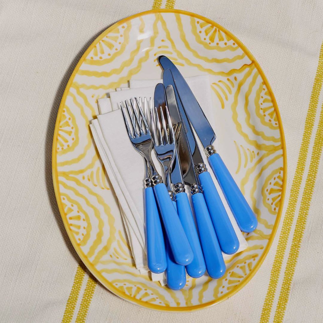 ```html
<img src="image.jpg" alt="Blue-handled cutlery set with knives and forks on a patterned yellow plate, placed on white napkins." />
```