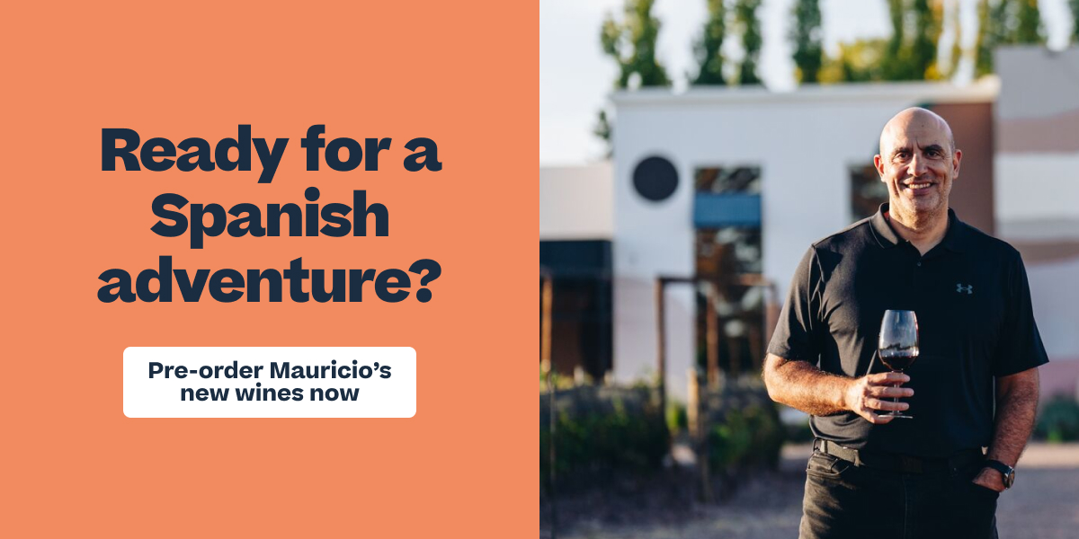 A smiling bald man in a black polo holding a wine glass outdoors, beside text reading "Ready for a Spanish adventure? Pre-order Mauricio's new wines now."