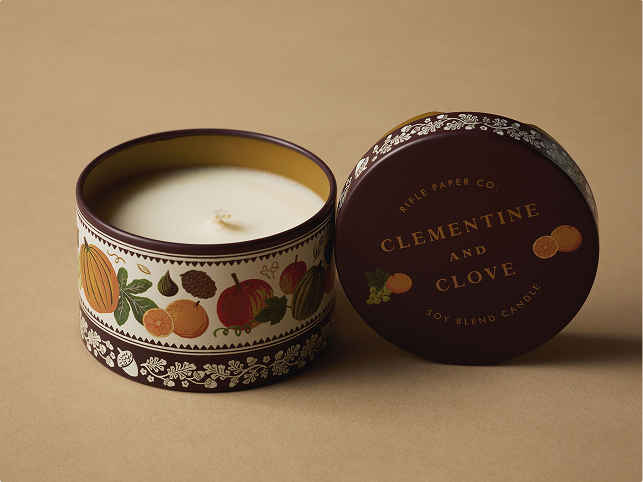 Rifle Paper Co. Clementine and Clove soy blend candle in a decorative tin with autumn fruit illustrations