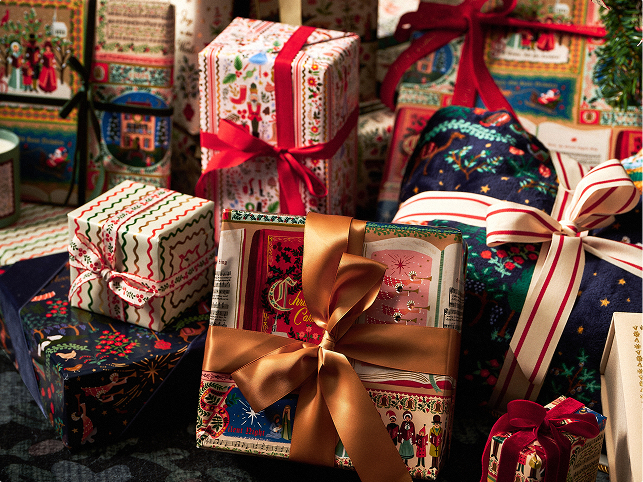 A variety of wrapped Christmas gifts featuring colorful patterns and ribbons are arranged together.