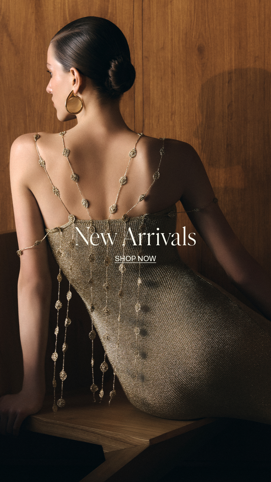 Woman wearing a gold metallic dress with crochet flower details and hoop earrings, shown from behind, "New Arrivals - Shop Now" text overlay.