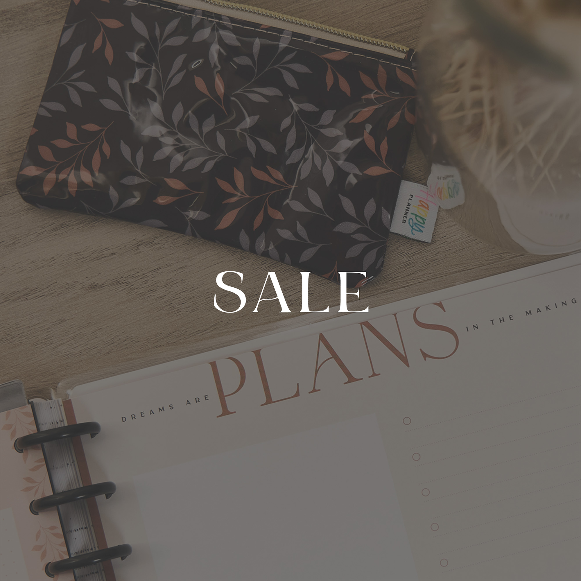 ```html
<img src="image.jpg" alt="Desk with floral pouch and planner, overlaid text 'SALE'." />
```