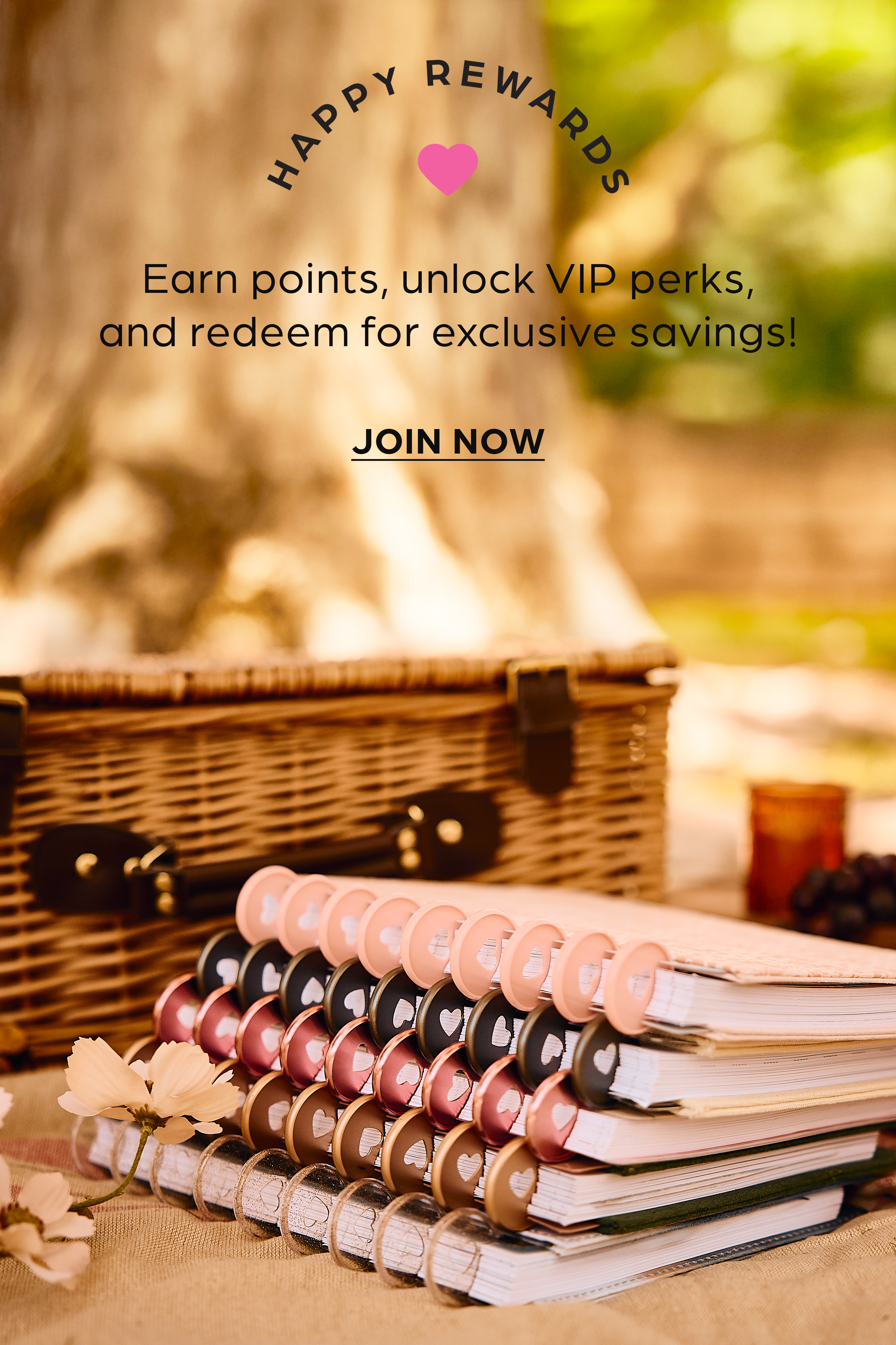Stacked spiral notebooks with heart-design discs beside a wicker basket, promoting a Happy Rewards loyalty program with VIP perks.