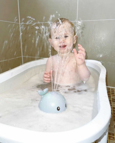 Barn i badet med en lysende Badehval